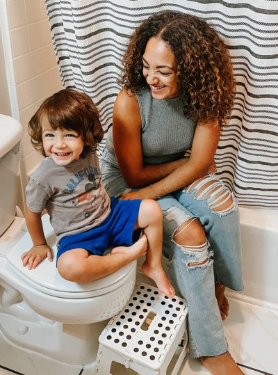 Mother sitting on tub in bathroom with smiling toddler son sitting on toilet Mother sitting on tub in bathroom with smiling toddler son sitting on toilet